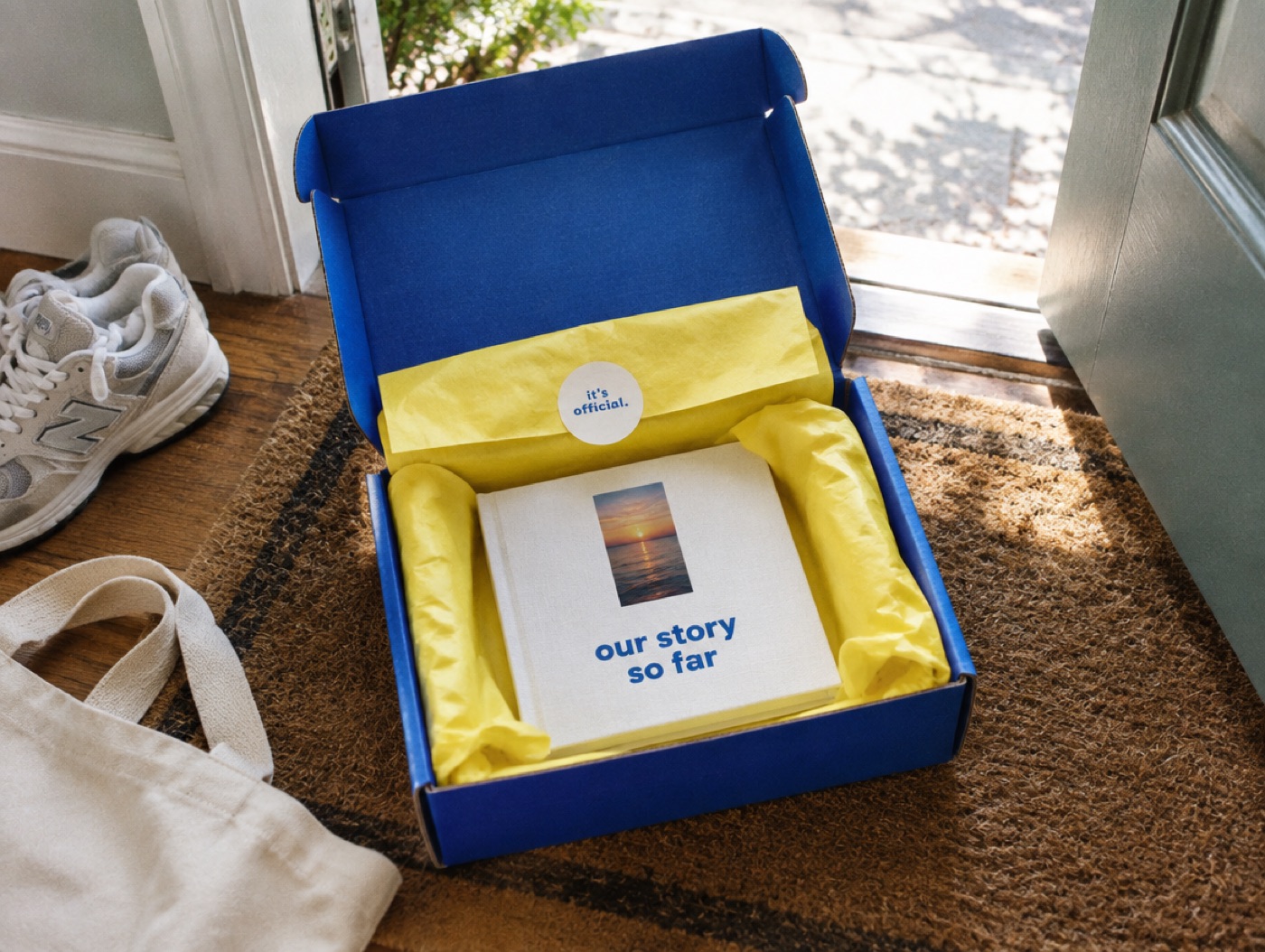 A cobalt mailer box opened on a doormat, with yellow tissue and a sticker that says it's official.